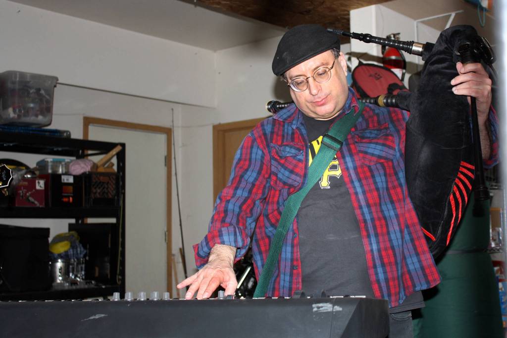 Mike Barnhill shoulders his bagpipes to play the keyboard during a Fire on McGinnis practice Saturday, March 9, 2019. (Ben Hohenstatt | Capital City Weekly)