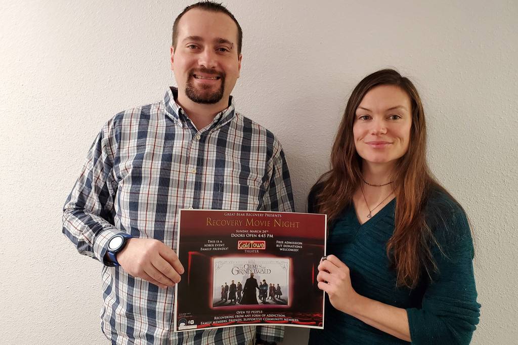 Carrie Amott, a board member of the Great Bear Recovery Collective, and Mike VanLinden, re-entry case manager for Great Bear Recovery Collective, hold up a poster for their organizations upcoming movie night. (Courtesy Photo | Great Bear Recovery Collective)
