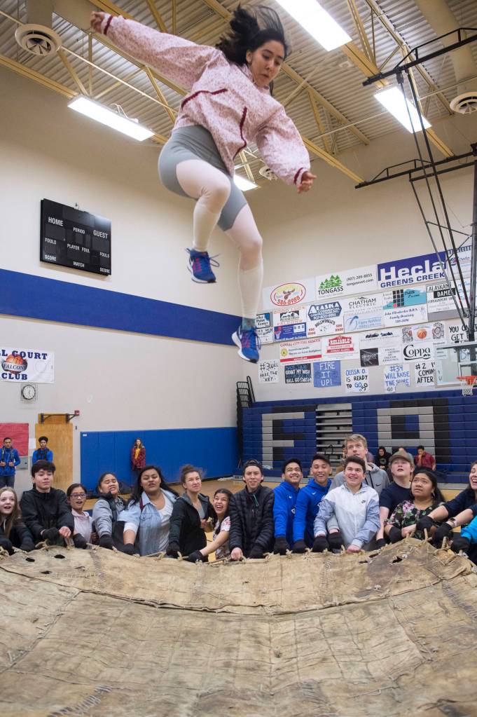 Native Youth Olympics athlete Sara Steeves, a senior at Thunder Mountain High School, takes to the air in a blanket toss demonstration during the lunch hour in the Thunder Mountain High School gymnasium on Friday, March 15, 2019. (Michael Penn | Juneau Empire)