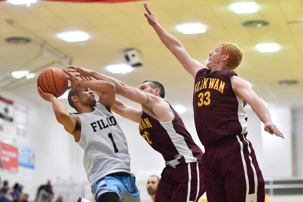 Klukwans Michael Ganey, center, and Jesse McGraw, right, keep Filcoms Larry Cooper rom scoring in their C bracket game at the Lions Clubs Gold Medal Basketball Tournament on Thursday, March 21, 2019. (Michael Penn | Juneau Empire)