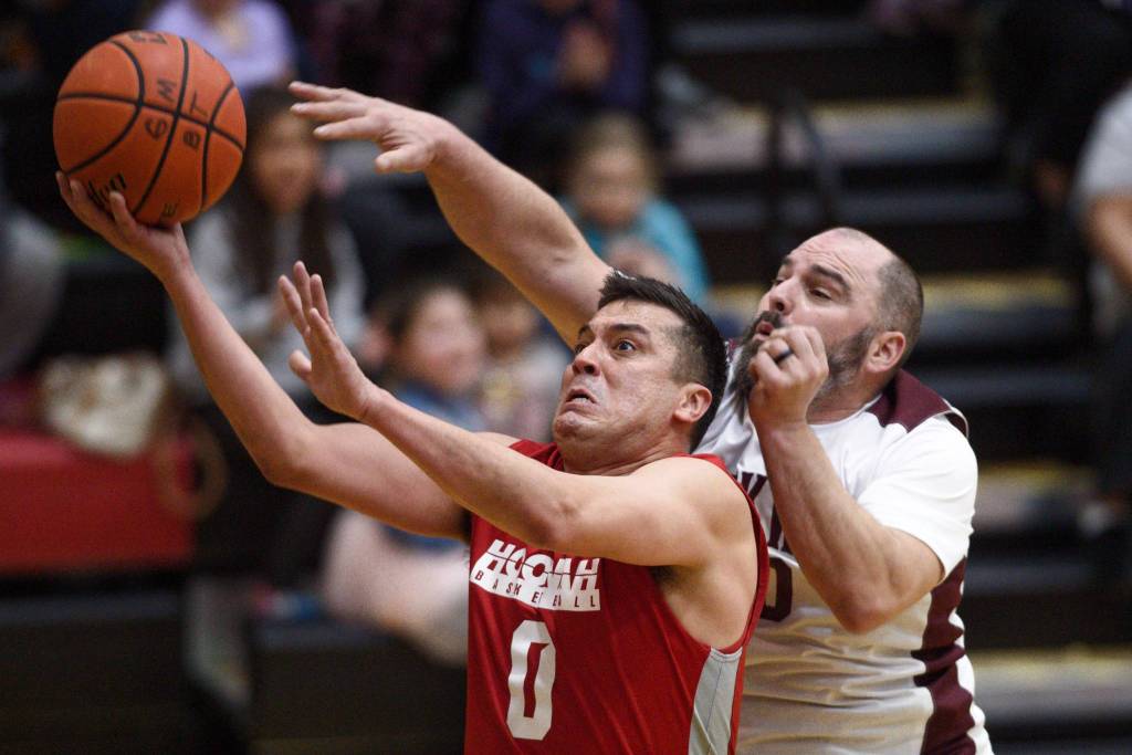 Hoonahs Anthony Lindoff, left, lays the ball up against Klukwans Stuart DeWitt in their C bracket game at the Gold Medal Basketball Tournament on Friday, March 22, 2019. (Michael Penn | Juneau Empire)