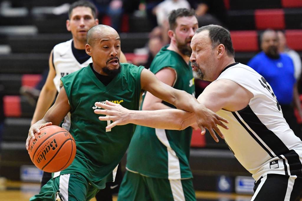 Sitkas Jeff Richards, left, drives against Yakutats Greg Indreland in their Masters bracket game at the Juneau Lions Club Gold Medal Basketball Tournament at JDHS on Wednesday, March 20, 2019. (Michael Penn | Juneau Empire)