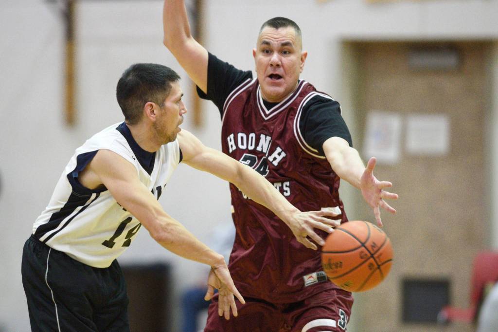 Yakutats Ralph Johnson, left, passes against Hoonahs James Mercer in the Masters bracket game at the Gold Medal Basketball Tournament on Thursday, March 21, 2019. (Michael Penn | Juneau Empire)