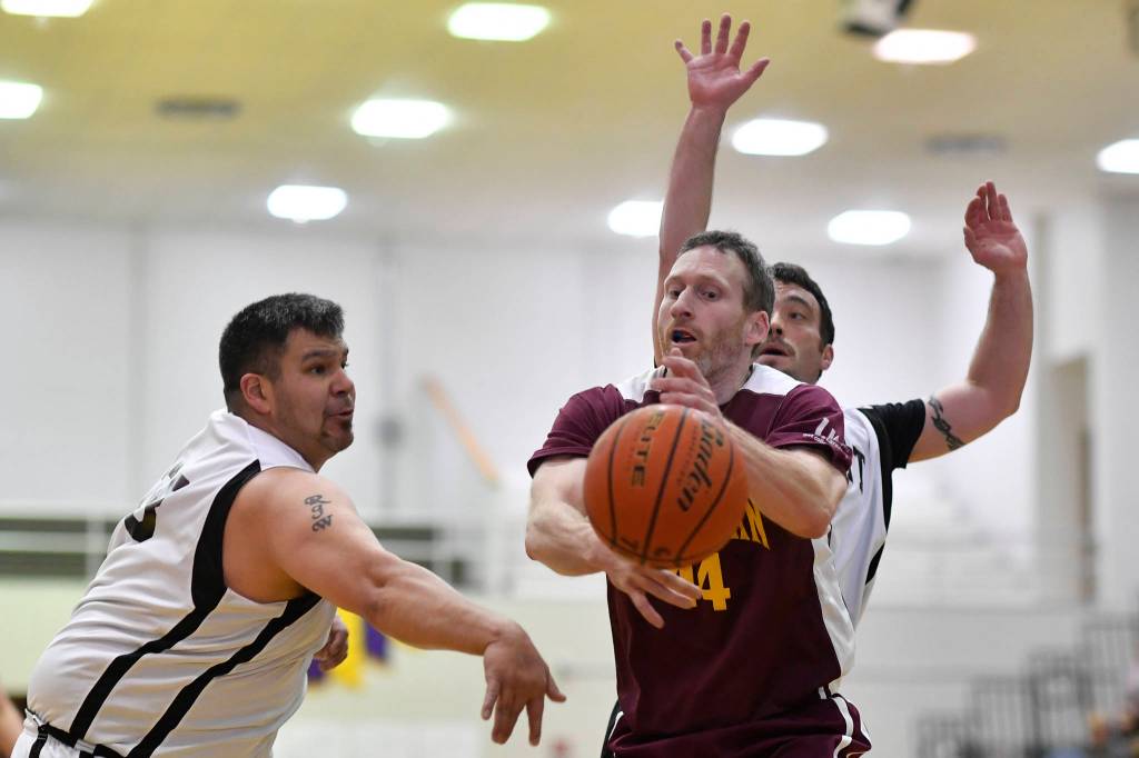 Klukwans Andrew Friske, center, has the ball batted away by Yakutats Ralph Wolfe, left, at the Juneau Lions Club 73rd Annual Gold Medal Basketball Tournament at Juneau-Douglas High School: Yadaa.at Kalé on Tuesday, March 19, 2019. Klukwan won 94-61. (Michael Penn | Juneau Empire)