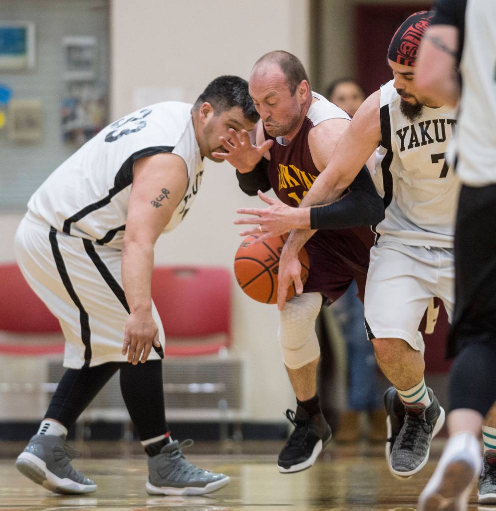 Klukwans Jason Shull, center, is sandwiched by Yakutats Ralph Wolfe, left, and JP Buller at the Juneau Lions Club 73rd Annual Gold Medal Basketball Tournament at Juneau-Douglas High School: Yadaa.at Kalé on Tuesday, March 19, 2019. Klukwan won 94-61. (Michael Penn | Juneau Empire)