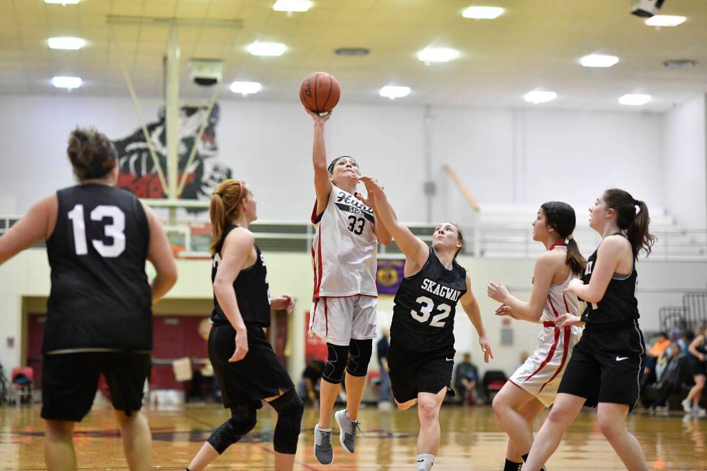 Hoonahs Krissy Benn, center, shoots between Skagways Jessie Ellis, left, and Savannah Ames at the Juneau Lions Club 73rd Annual Gold Medal Basketball Tournament at Juneau-Douglas High School: Yadaa.at Kalé on Tuesday, March 19, 2019. Skagway won 80-42. (Michael Penn | Juneau Empire)