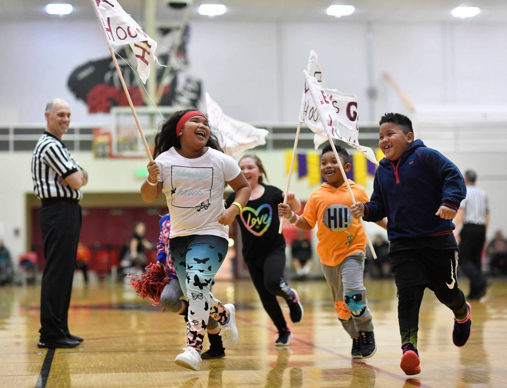 Children with Hoonah flags parade around the gymnasium during a break in the womens game against Skagway at the Juneau Lions Club 73rd Annual Gold Medal Basketball Tournament at Juneau-Douglas High School: Yadaa.at Kalé on Tuesday, March 19, 2019. Skagway won 80-42. (Michael Penn | Juneau Empire)