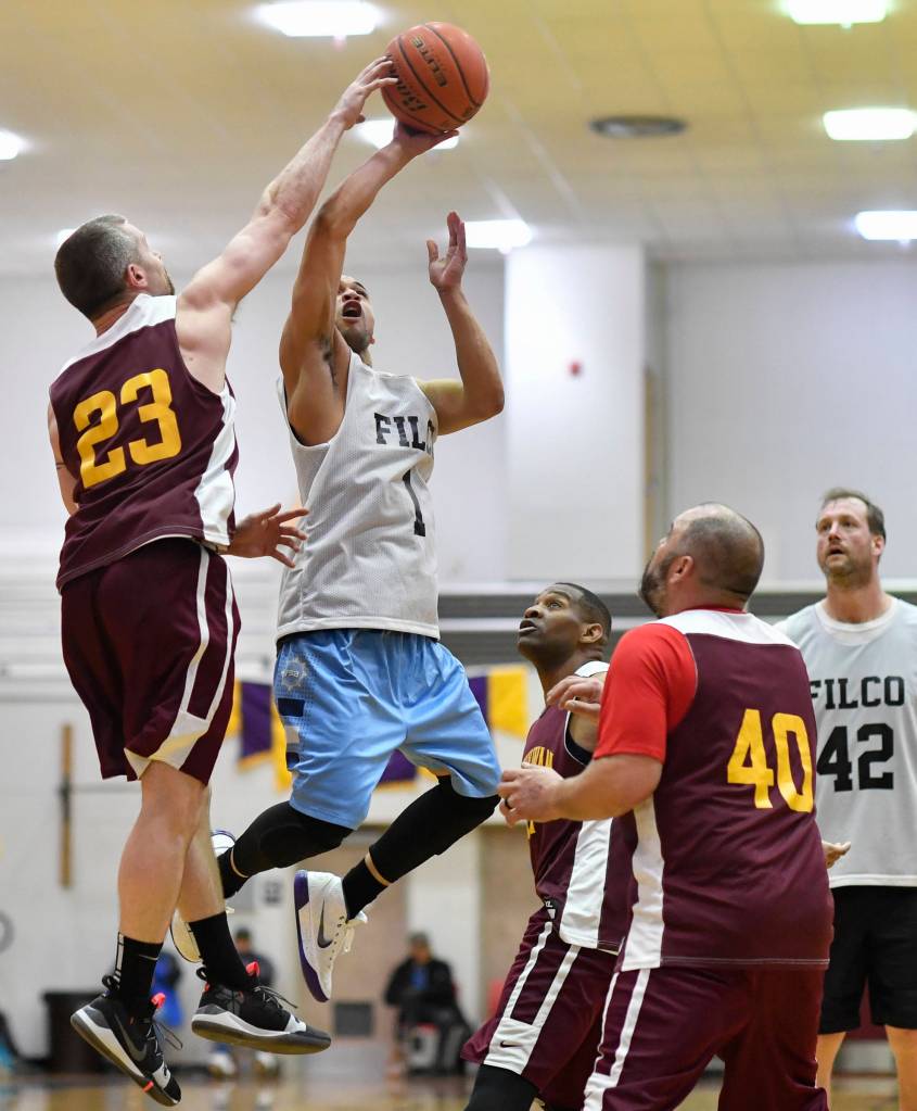 Klukwans Michael Ganey, left, blocks a shot by Filcoms Larry Cooper in their C bracket game at the Gold Medal Basketball Tournament on Thursday, March 21, 2019. (Michael Penn | Juneau Empire)