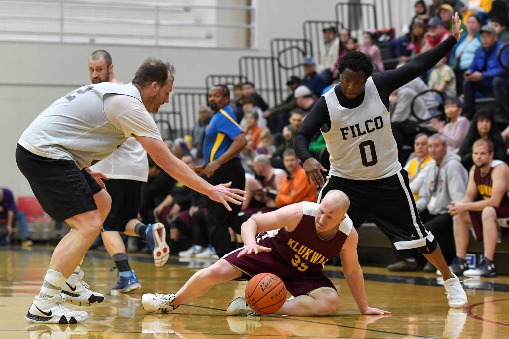 Klukwans Brian Friske, center, dives for the ball against Filcoms Greg Lockwood, left, ad Rob Ridgeway in their C bracket game at the Gold Medal Basketball Tournament on Thursday, March 21, 2019. (Michael Penn | Juneau Empire)