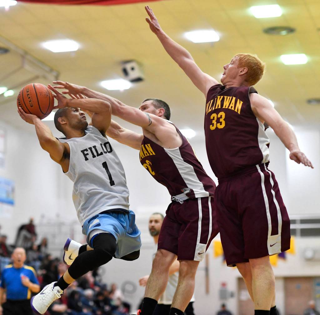 Klukwans Michael Ganey, center, and Jesse McGraw keep Filcoms Larry Cooper from scoring in their C bracket game at the Gold Medal Basketball Tournament on Thursday, March 21, 2019. (Michael Penn | Juneau Empire)