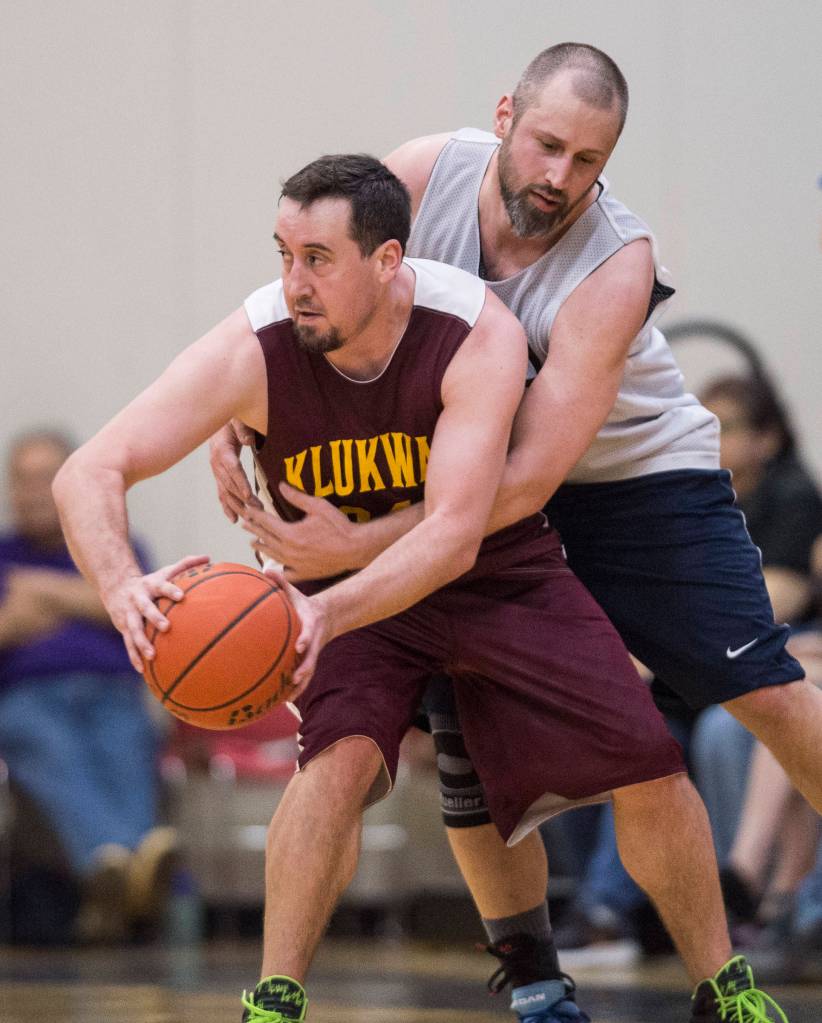 Filcoms Ray Zimmer, right, fouls Klukwans Chris Dixon in their C bracket game at the Gold Medal Basketball Tournament on Thursday, March 21, 2019. (Michael Penn | Juneau Empire)