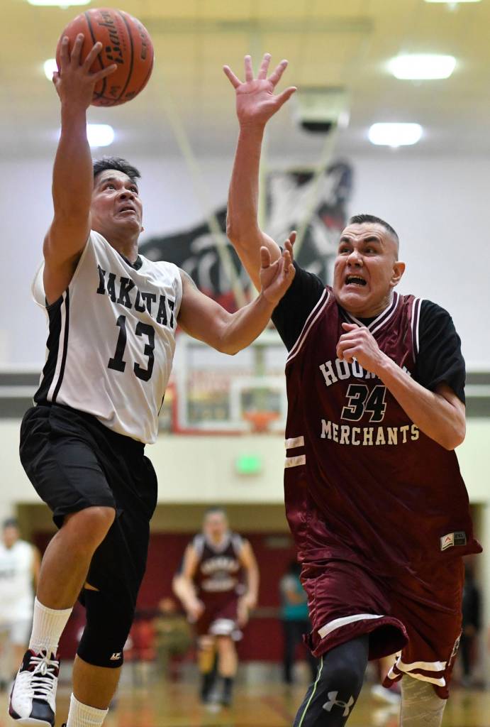 Yakutats Jerry Riddington, left, lays the ball up against Hoonahs James Mercer in the Masters bracket game at the Gold Medal Basketball Tournament on Thursday, March 21, 2019. (Michael Penn | Juneau Empire)
