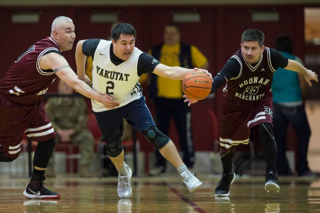 Yakutats Anthony Mallott, center, dribbles away from Hoonahs Ed Mercer, left, and Kamal Lindoff in the Masters bracket game at the Gold Medal Basketball Tournament on Thursday, March 21, 2019. (Michael Penn | Juneau Empire)