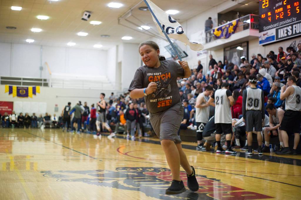 A young fan runs with runs with a Angoon flag in between the first and second quarters of Angoons B Bracket game against Metlakatla. (Nolin Ainsworth | Juneau Empire)
