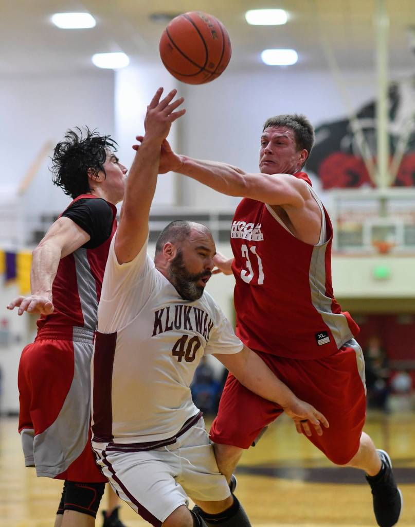 Klukwans Stuart DeWitt, center, attempts to score on Hoonahs Donald Dybdahl, left, and Greg Strout during their C bracket game at the Juneau Lions Club 73rd Annual Gold Medal Basketball Tournament at Juneau-Douglas High School on Friday, March 22, 2019. Klukwan won 88-67. (Michael Penn | Juneau Empire)