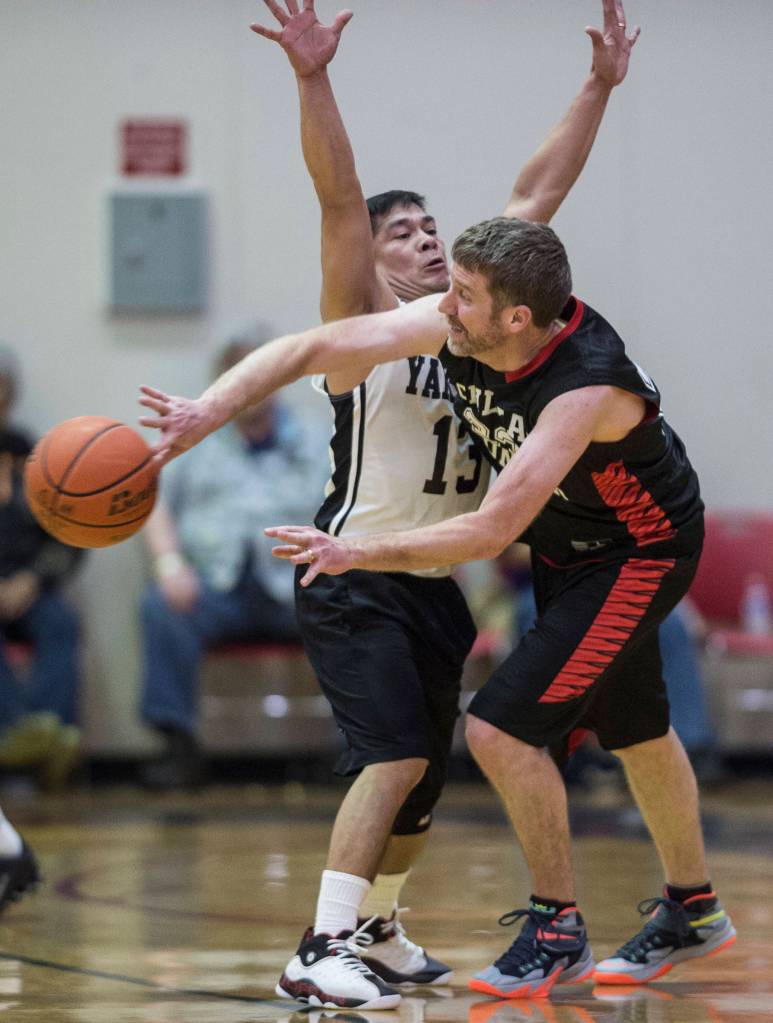 Haines Dave Buss, right, passes around Yakutats Jerry Riddington during their Masters bracket game at the Juneau Lions Club 73rd Annual Gold Medal Basketball Tournament at Juneau-Douglas High School on Friday, March 22, 2019. Klukwan won 63-58. (Michael Penn | Juneau Empire)