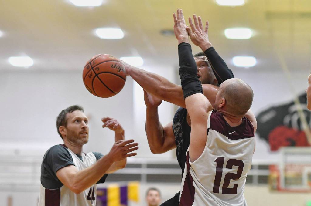 Hydaburgs Kevin Young has his shot blocked by Klukwans Andrews Friske, left, and Jason Shull in the C bracket final at the Gold Medal Basketball Tournament on Saturday, March 23, 2019. (Michael Penn | Juneau Empire)