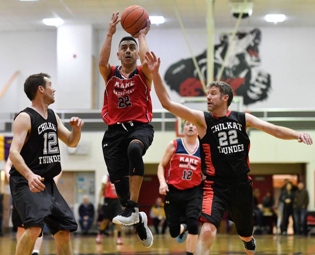 Kakes Jay Peterson, center, drives to the basket between Klukwans Steve Forbes, left, and Dave Buss in the Masters final at the Gold Medal Basketball Tournament on Saturday, March 23, 2019. Kake won 75-64. (Michael Penn | Juneau Empire)