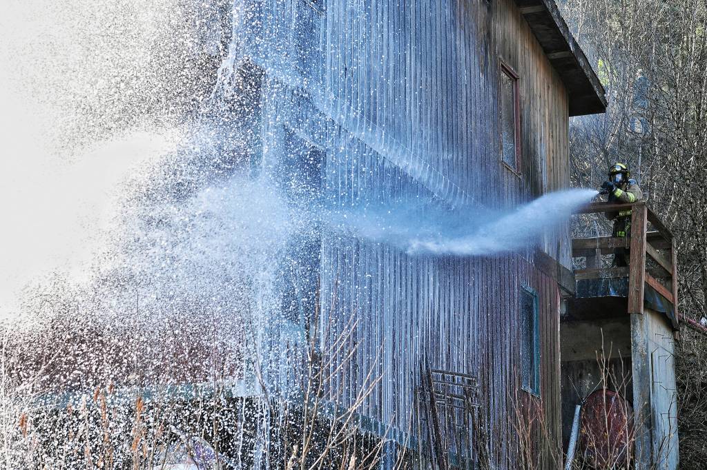 Firefighters knock down the last flames of a house fire on North Douglas Highway on Thursday, March 29, 2019. (Michael Penn | Juneau Empire)
