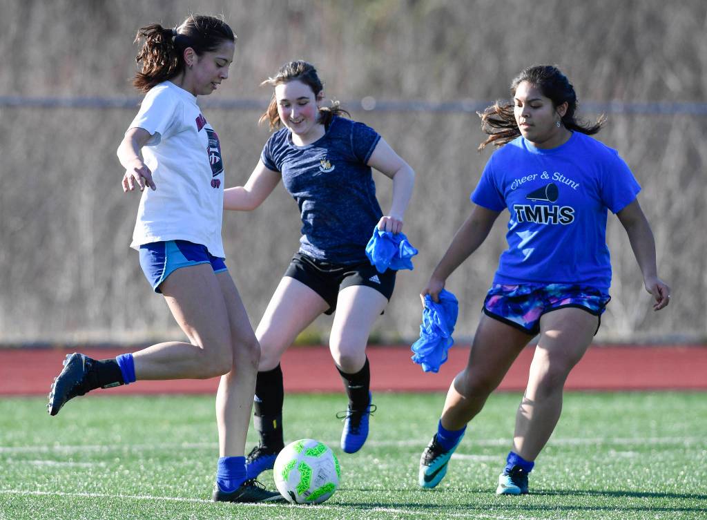 Keana Villanueva, left, keeps the ball away from Alina Renz, center, and Ferlyn Dimasaca during Thunder Mountain High School girls soccer practice on Friday, March 29, 2019. (Michael Penn | Juneau Empire)