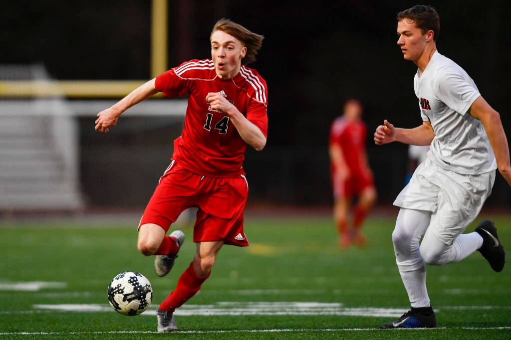 Juneau-Douglas Kanon Goetz, left, races against Clarksons Nate Hoffman at Adair-Kennedy Memorial Field on Wednesday, April 3, 2019. Clarkson won 1-0. (Michael Penn | Juneau Empire)