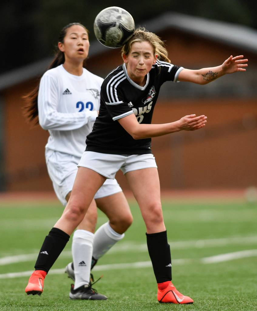 Juneau-Douglas Jessie Mayer heads the ball away from Thunder Mountains Molly Brocious at Adair-Kennedy Memorial Field on Wednesday, April 3, 2019. JDHS won 8-0. (Michael Penn | Juneau Empire)