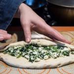 Erin Anais Heist prepares and bakes a khachapuri with nettles, feta and mozzarella cheese and topped with an egg on Friday, April 12, 2019. (Michael Penn | Juneau Empire)