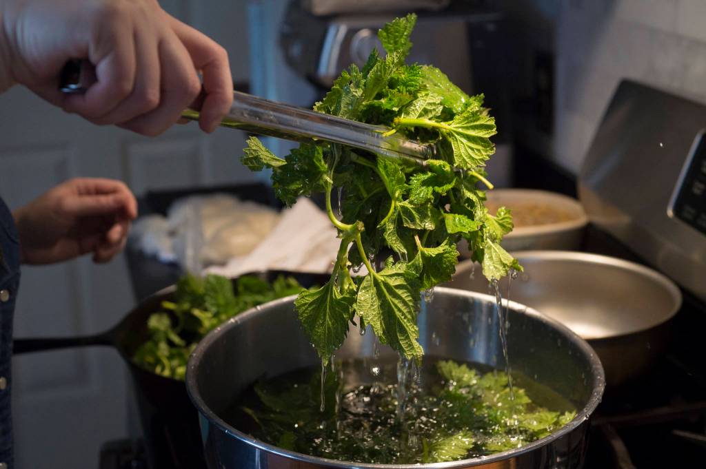 Erin Anais Heist prepares and bakes a khachapuri with nettles, feta and mozzarella cheese and topped with an egg on Friday, April 12, 2019. (Michael Penn | Juneau Empire)