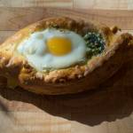 Erin Anais Heist prepares and bakes a khachapuri with nettles, feta and mozzarella cheese and topped with an egg on Friday, April 12, 2019. (Michael Penn | Juneau Empire)