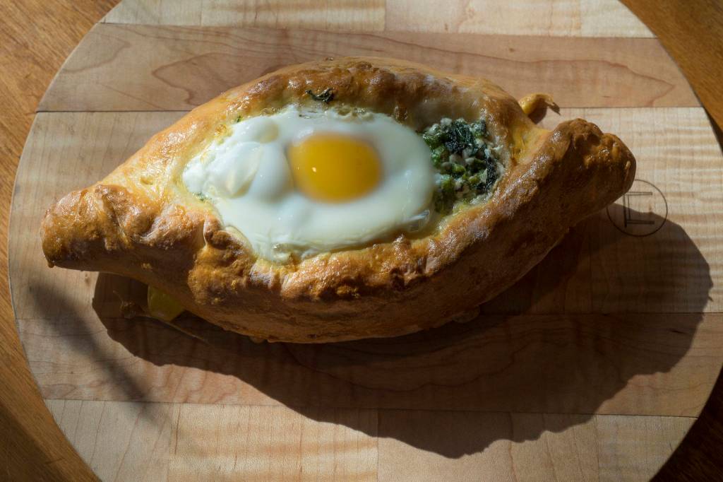 Erin Anais Heist prepares and bakes a khachapuri with nettles, feta and mozzarella cheese and topped with an egg on Friday, April 12, 2019. (Michael Penn | Juneau Empire)