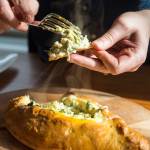 Erin Anais Heist prepares and bakes a khachapuri with nettles, feta and mozzarella cheese and topped with an egg on Friday, April 12, 2019. (Michael Penn | Juneau Empire)