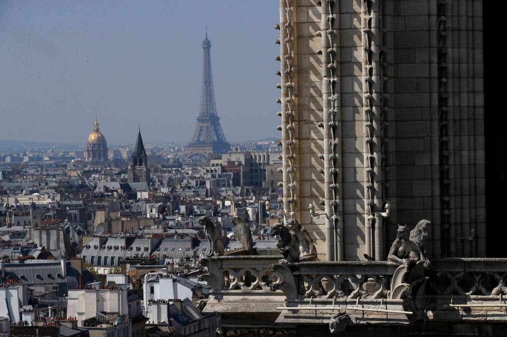 View from the top of the Paris Notre Dame Cathedral with the Eiffel Tower in background as the religious statues descend to earth for the first time in over a century as part of a restoration, in Paris Thursday, April 11, 2019. The 16 greenish-gray copper statues, which represent the twelve apostles and four evangelists, are lowered by a 100 meter (105 yard) crane onto a truck to be taken for restoration in southwestern France. (AP Photo/Francois Mori)