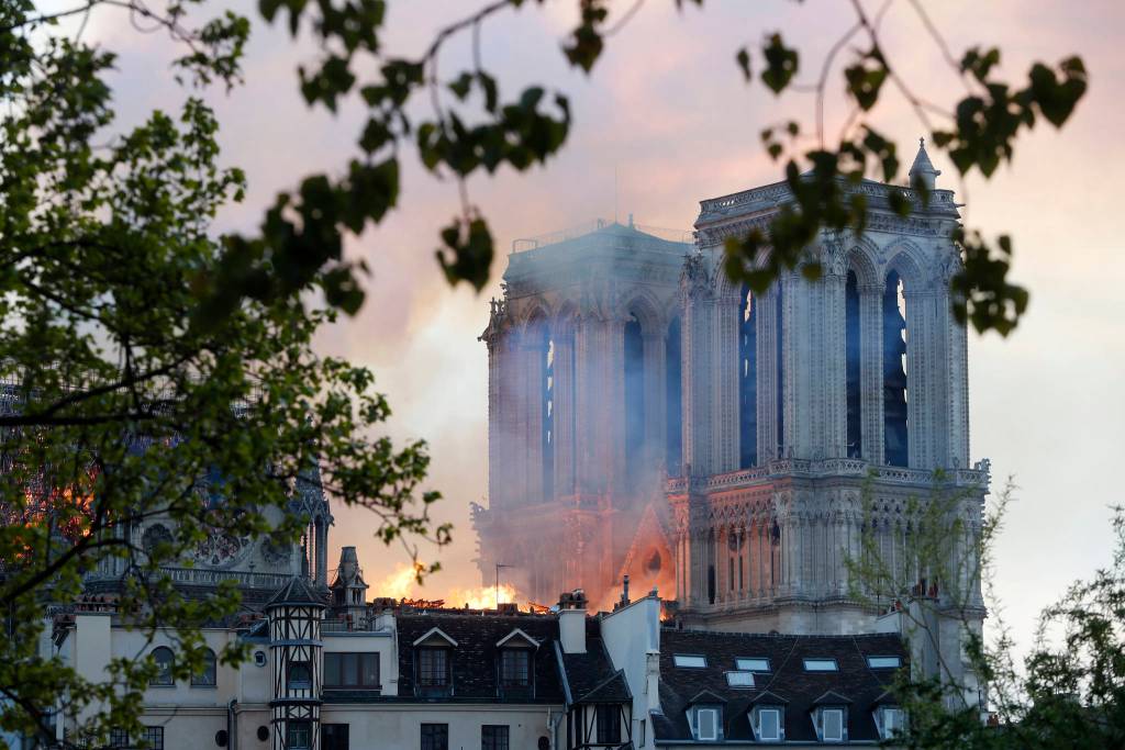 Flames rise from Notre Dame cathedral as it burns in Paris, Monday, April 15, 2019. Massive plumes of yellow brown smoke is filling the air above Notre Dame Cathedral and ash is falling on tourists and others around the island that marks the center of Paris. (AP Photo/Thibault Camus)