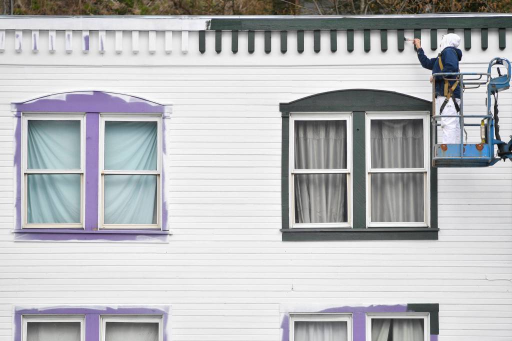 A Herrs Painting employee hand paints the trim on the front of Tanzanite International on Monday, April 15, 2019. (Michael Penn | Juneau Empire)