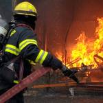 A firefighter readies to spray flames underneath The Gym, a Glacier Avenue gym, Monday, April 22, 2019. (Ben Hohenstatt | Juneau Empire)