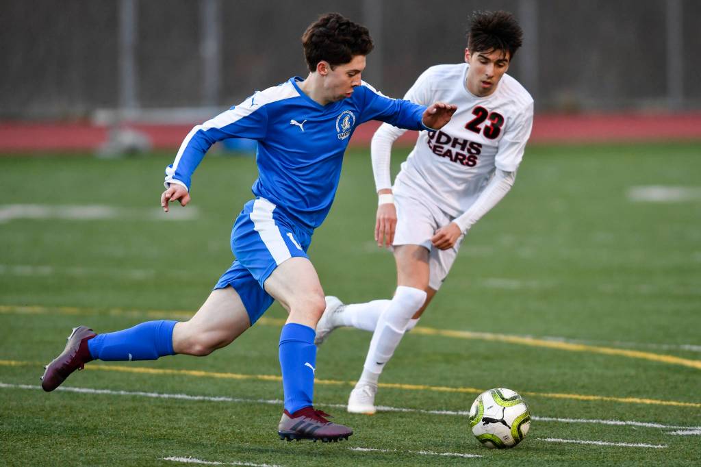 Thunder Mountains Jake Babcock, left, races against Juneau-Douglas Kaiden Wilshusen during their game at TMHS on Tuesday, April 23, 2019. JDHS won 2-0. (Michael Penn | Juneau Empire)