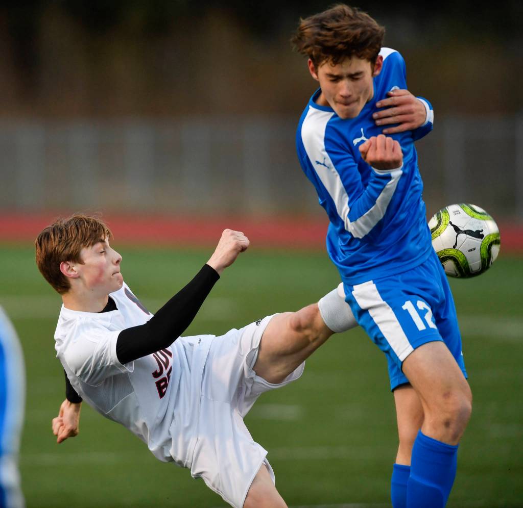 Thunder Mountains Wallace Adams, right, blocks a shot by Juneau-Douglas Koby Goldstein during their game at TMHS on Tuesday, April 23, 2019. JDHS won 2-0. (Michael Penn | Juneau Empire)