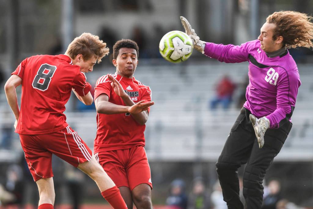 Juneau-Douglas Koby Goldstein, left, heads the ball against Soldotnas goal keeper Hunter Woodward at Adair-Kennedy Memorial Field on Friday, April 26, 2019. Juneau-Douglas Finn Yerkes is center. JDHS won 6-0. (Michael Penn | Juneau Empire)