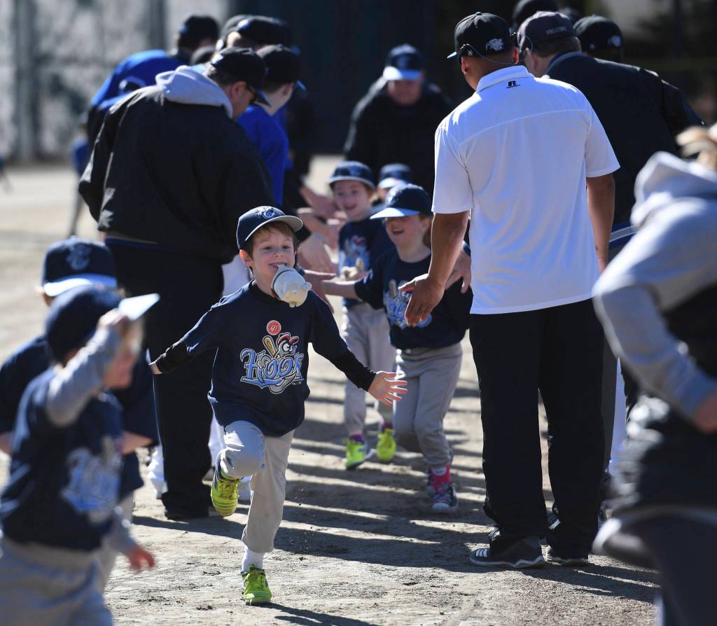 Players run a gauntlet of Thunder Mountain High School baseball and softball team players during the Gastineau Channel Little League Opening Day Ceremonies at Adair-Kennedy Memorial Park on Saturday, April 27, 2019. (Michael Penn | Juneau Empire)