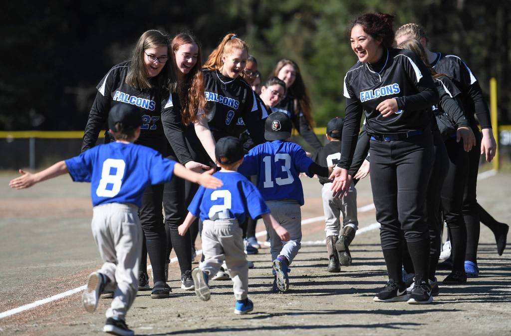 Players run a gauntlet of Thunder Mountain High School baseball and softball team players during the Gastineau Channel Little League Opening Day Ceremonies at Adair-Kennedy Memorial Park on Saturday, April 27, 2019. (Michael Penn | Juneau Empire)