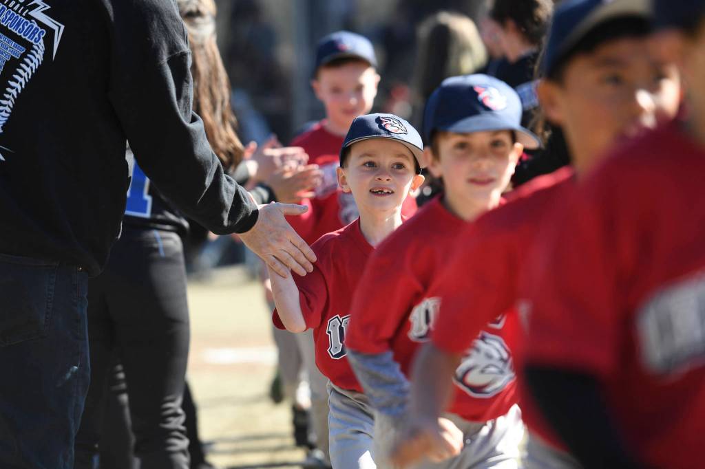 Players run a gauntlet of Thunder Mountain High School baseball and softball team players during the Gastineau Channel Little League Opening Day Ceremonies at Adair-Kennedy Memorial Park on Saturday, April 27, 2019. (Michael Penn | Juneau Empire)