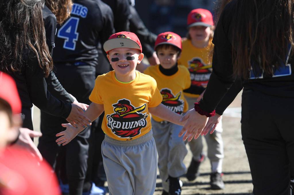 Players run a gauntlet of Thunder Mountain High School baseball and softball team players during the Gastineau Channel Little League Opening Day Ceremonies at Adair-Kennedy Memorial Park on Saturday, April 27, 2019. (Michael Penn | Juneau Empire)