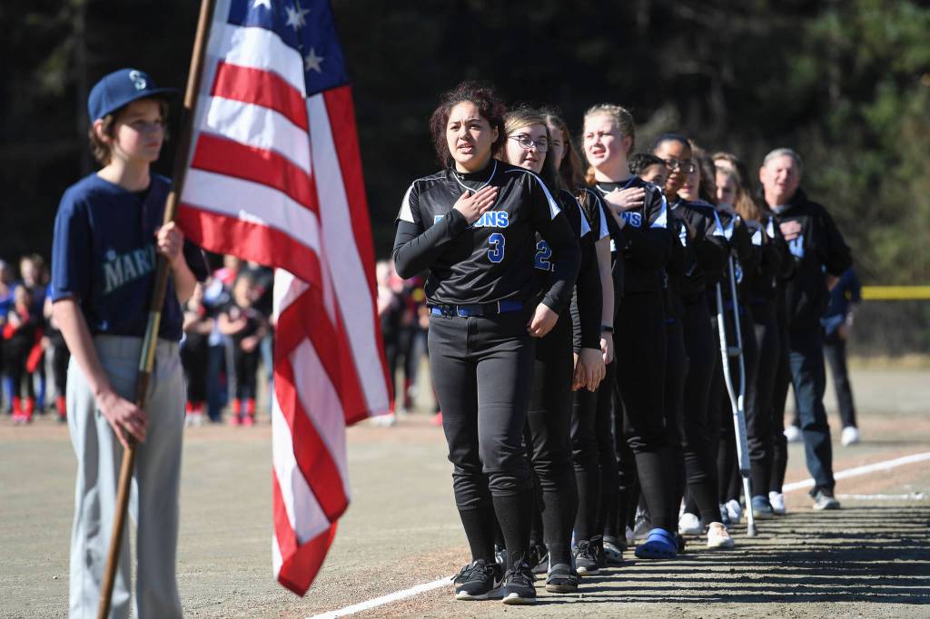 John Polasky holds the U.S.A. flag in front of Thunder Mountain High School softball team during the Gastineau Channel Little League Opening Day Ceremonies at Adair-Kennedy Memorial Park on Saturday, April 27, 2019. (Michael Penn | Juneau Empire)