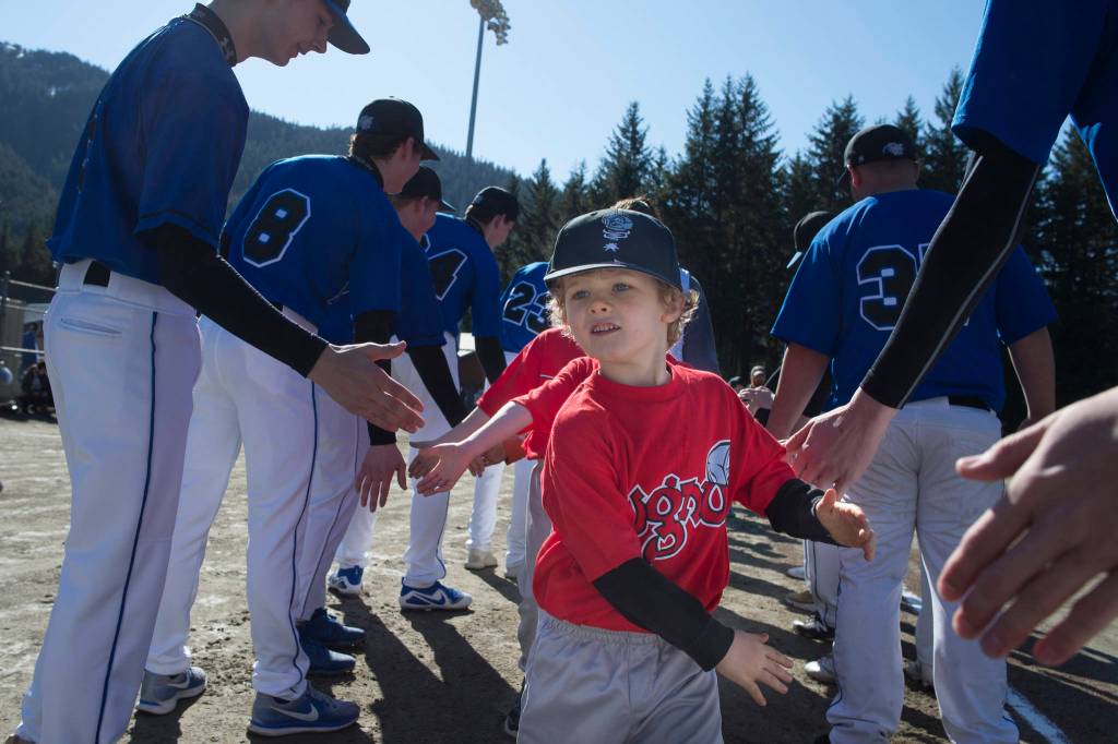 Players run a gauntlet of Thunder Mountain High School baseball and softball team players during the Gastineau Channel Little League Opening Day Ceremonies at Adair-Kennedy Memorial Park on Saturday, April 27, 2019. (Michael Penn | Juneau Empire)