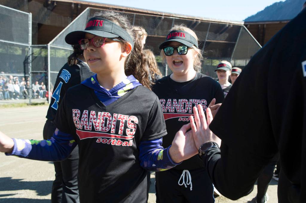 Players run a gauntlet of Thunder Mountain High School baseball and softball team players during the Gastineau Channel Little League Opening Day Ceremonies at Adair-Kennedy Memorial Park on Saturday, April 27, 2019. (Michael Penn | Juneau Empire)