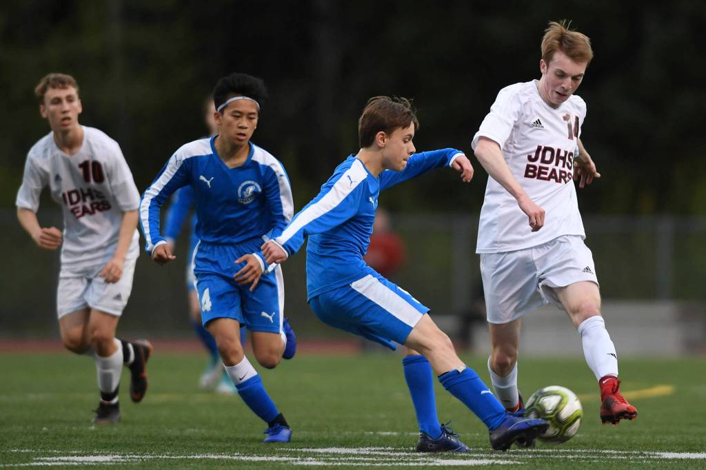 Thunder Mountains Elias West kicks the ball away from Juneau-Douglas Kanon Goetz at TMHS on Tuesday, May 14, 2019. JDHS won 5-1. (Michael Penn | Juneau Empire)