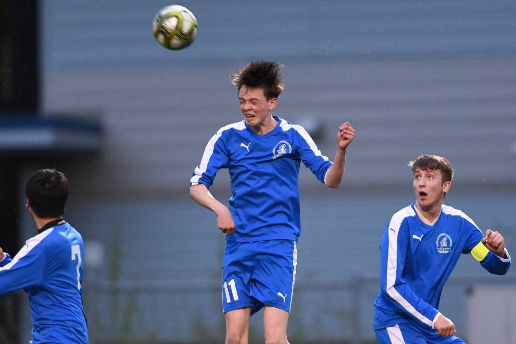 Thunder Mountains Talon Briggs, center, heads the ball against Juneau-Douglas flanked by teammates Bernanrd Yadao, left, and Kieran Kollar at TMHS on Tuesday, May 14, 2019. JDHS won 5-1. (Michael Penn | Juneau Empire)