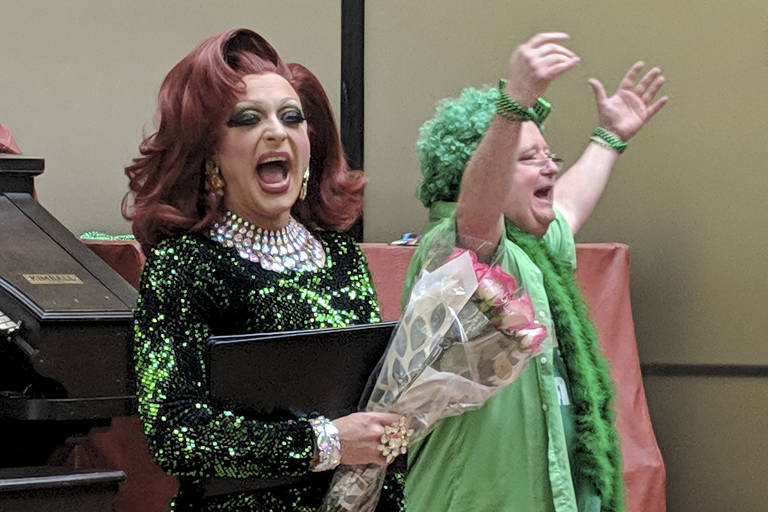 In this photo from March 15, 2019, Gigi Monroe, left, clutches a bouquet courtesy of organist T.J. Duffy, right, after a St. Patricks Day-themed performance at the State Office Building. (Ben Hohenstatt | Capital City Weekly)