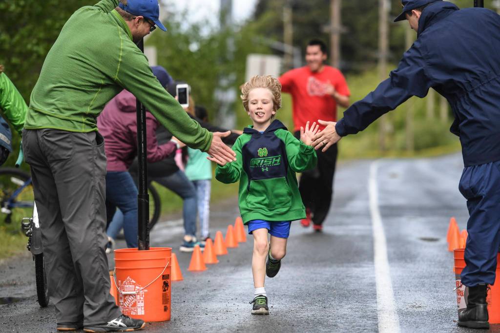 First-grader Gabe McGuan receives high-fives as he finishes Harborview Elementary Schools annual Fun Run along Glacier Avenue on Friday, May 17, 2019. Students from Montessori Borealis also ran the three-mile course. (Michael Penn | Juneau Empire)