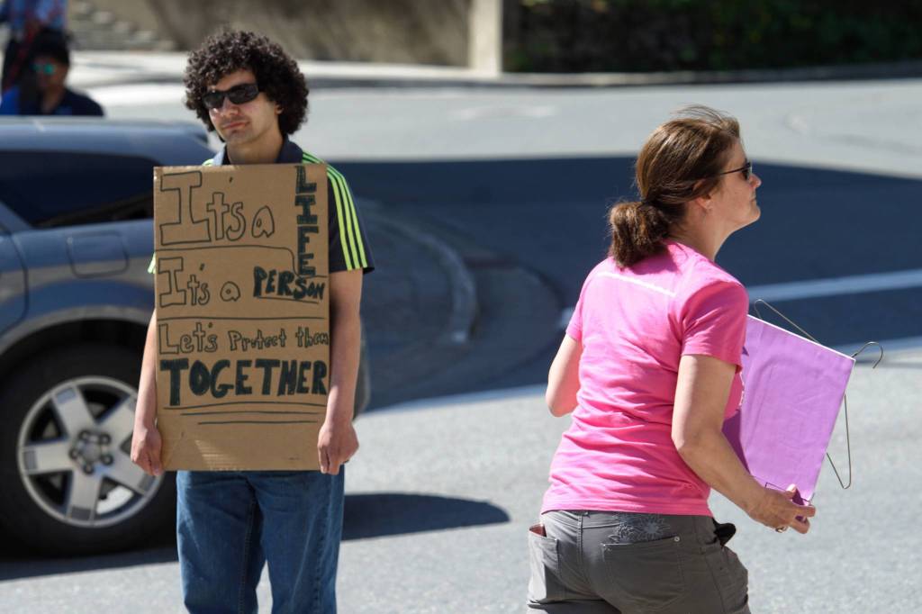 Tyler Riberio holds a counter protest during a rally against anti-abortion laws at the Dimond Courthouse Plaza on Tuesday, May 21, 2019. (Michael Penn | Juneau Empire)